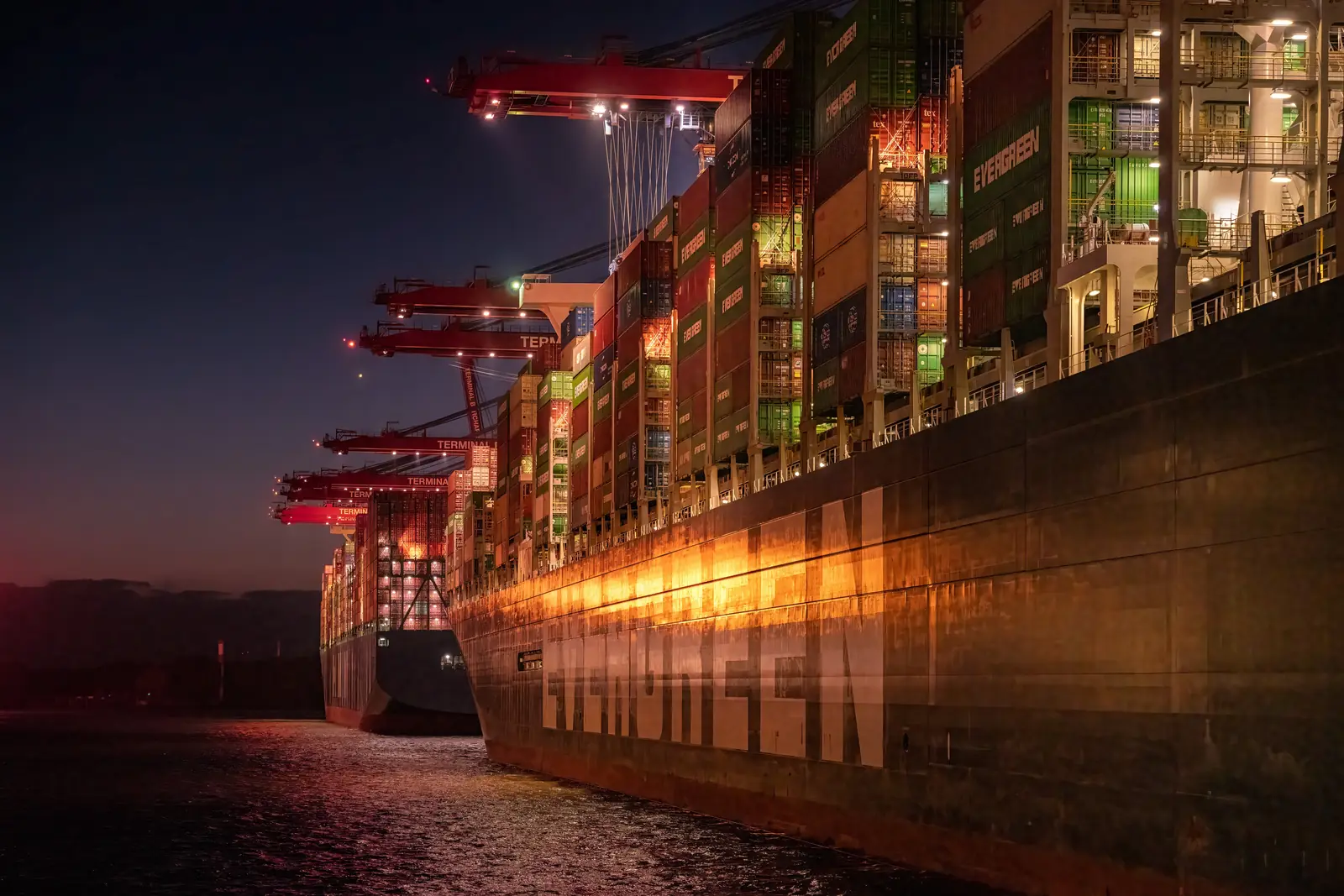 Beladenes Containerschiff nachts am Terminal im Hamburger Hafen